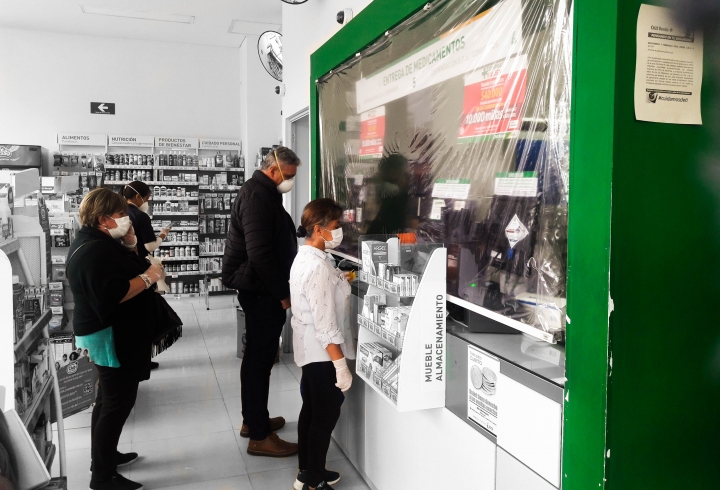 Distanciamiento entre los clientes y un pl&aacute;stico que separa a las cajeras de estos en una droguer&iacute;a Cruz Verde al norte de Bogot&aacute;