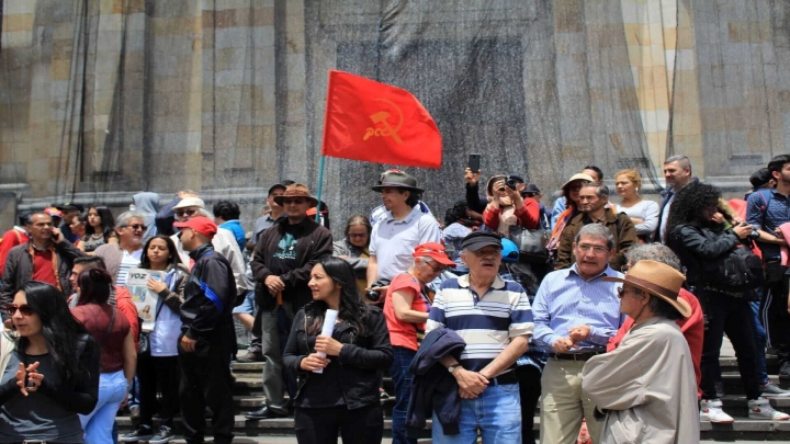 Manifestantes frente a la Catedral Primada con una bandera de la causa comunista