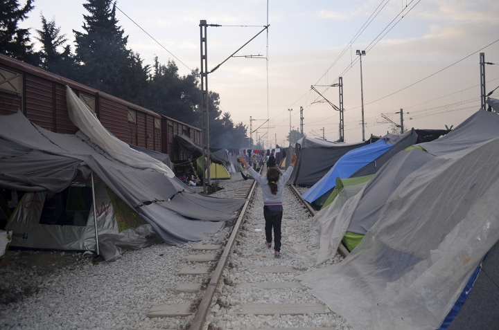 Niñas corren en medio del campo de Idomeni, que estaba compuesto por una antigua estación de tren con antiguos raíles y vagones (2016)