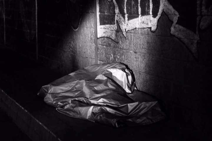 Un habitante de calle, escondido en una manta, en un puente de la calle 26 de Bogot&aacute;