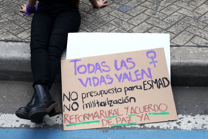 Mujer con pancarta sentada en el suelo