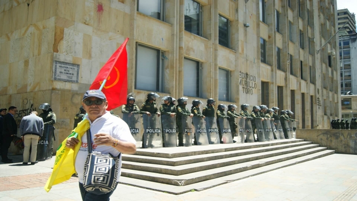 Miembro de Partido Comunista marcha en frente de efectivos de la Polic&iacute;a