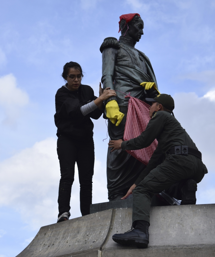 Una joven se montó en la estatua de Simón Bolívar en la Plaza de Bolívar y, bajo la consigna de que los hombres también entran a la cocina, lo vistieron con delantal y guantes para lavar la loza. A penas se dio cuenta la Policía, subieron un bachiller para que la bajara y le quitara los atuendos a la estatua. Foto: Santiago Luque