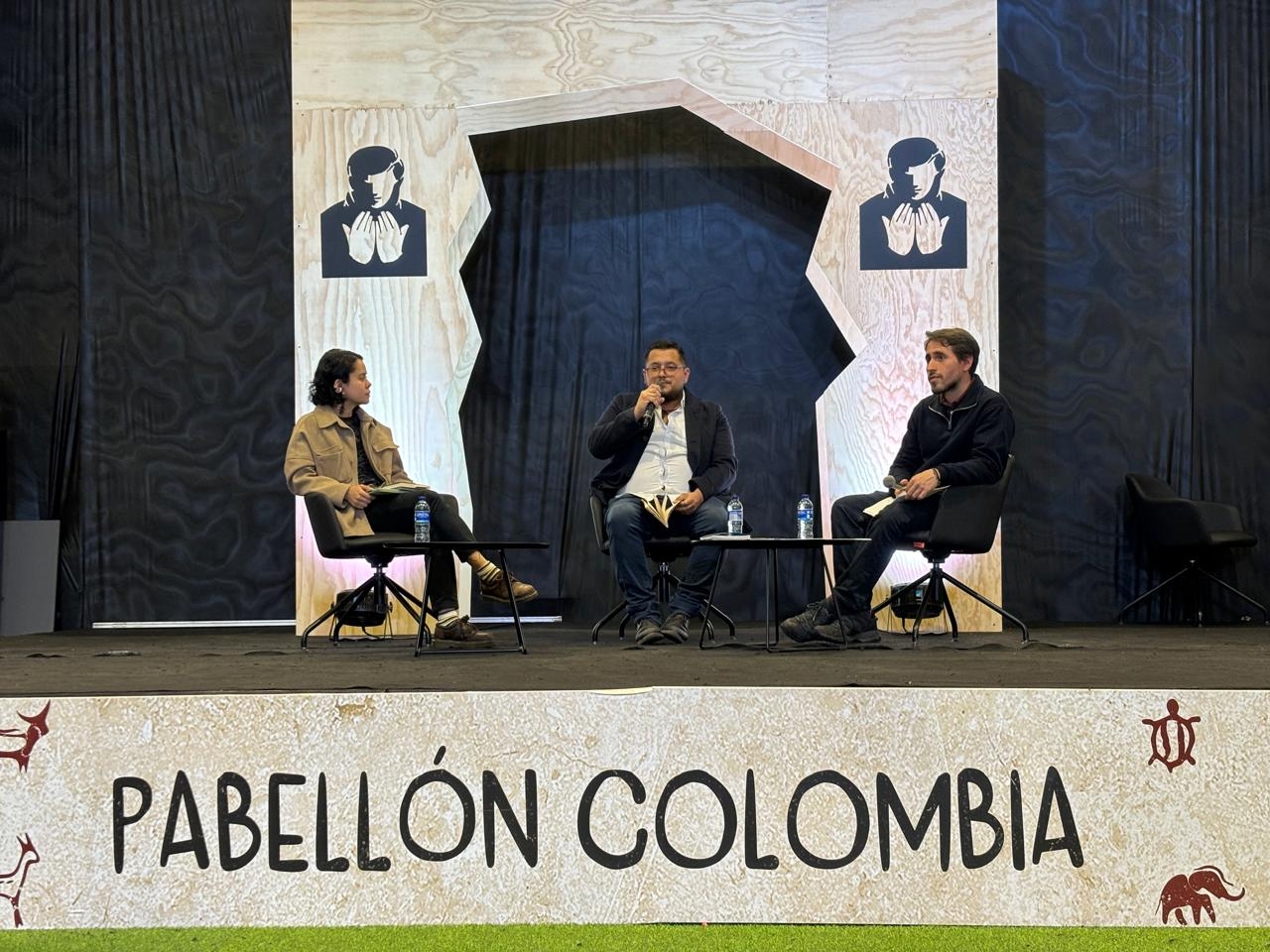 Ligia Trujillo, Jorge Carreño y Manuel Valdivieso sentados en la lectura de poemas en el pabellón Colombia.|||